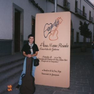 AMR Standing In Front Of Large Poster On The Street With Her Guitar