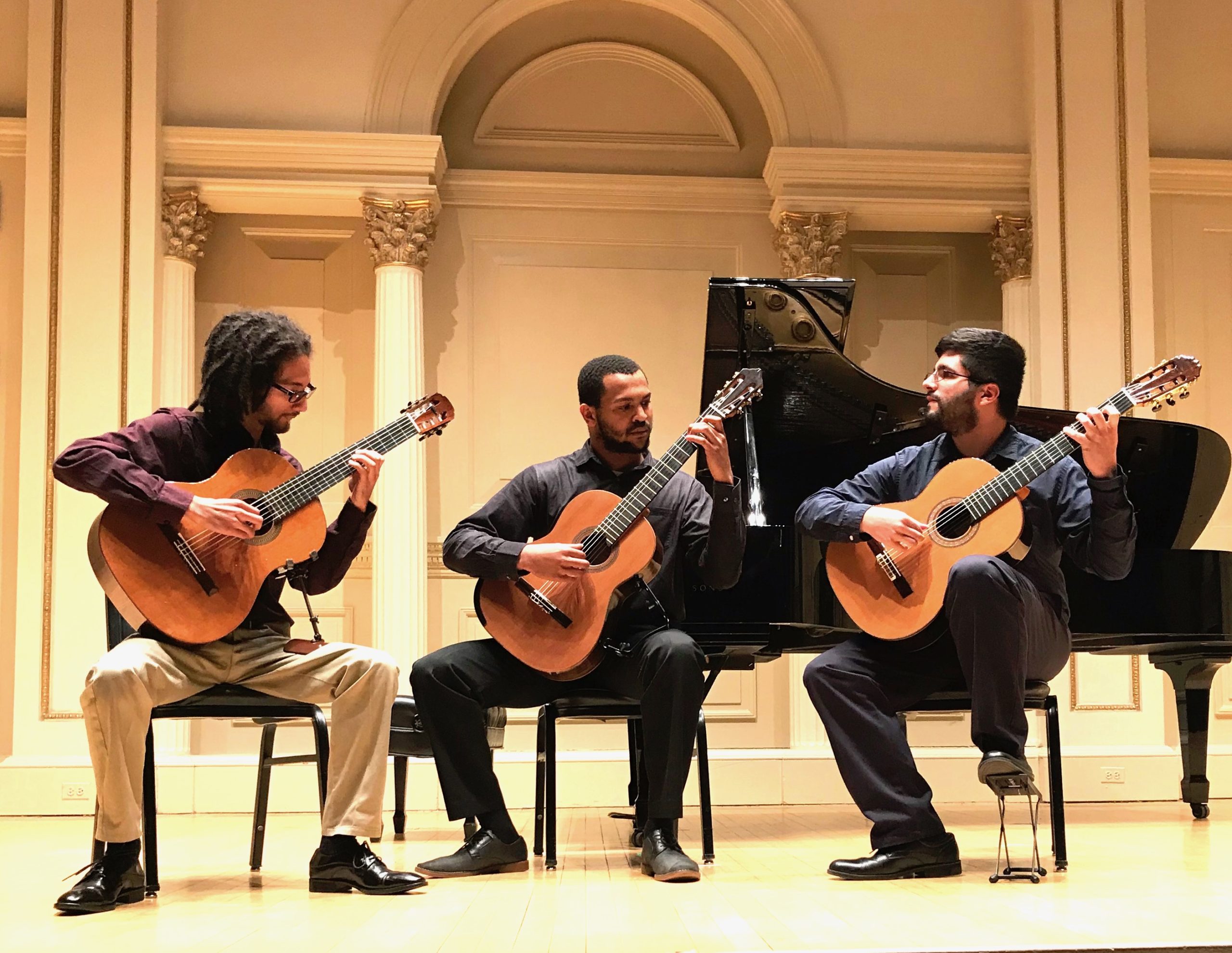 3 young men playing acoustic guitars on stage